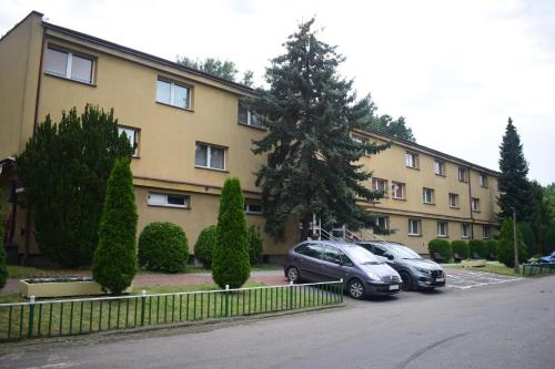 dwa samochody zaparkowane na parkingu przed budynkiem w obiekcie Hotel Skaut w mieście Chorzów