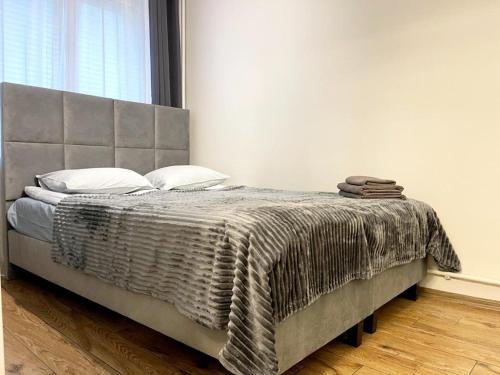 a bed with a gray blanket and pillows on it at Apartament Marina Hel in Hel
