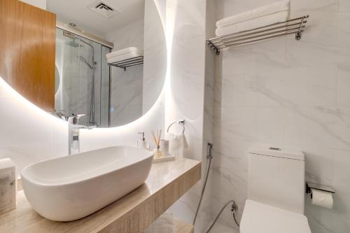 a white bathroom with a sink and a toilet at Luxury Apt - Rooftop Pool - City View in Dubai
