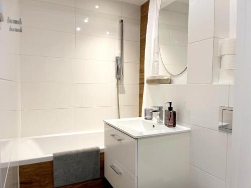 a white bathroom with a sink and a tub at Apartament Marina Hel in Hel