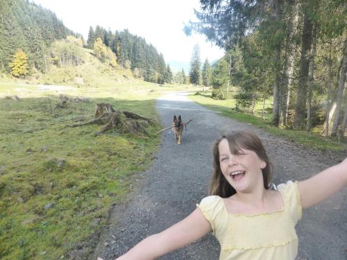 a young girl standing on a road with a dog at Haus Valder in Niedernsill
