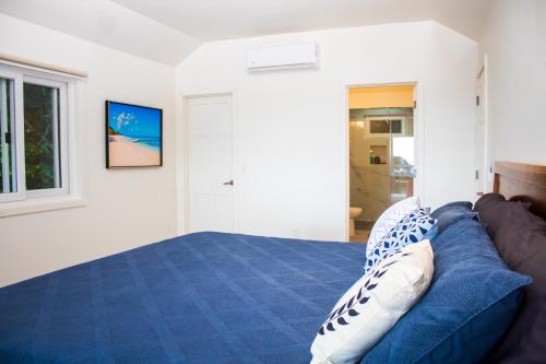 a bedroom with a blue bed and a window at Casa Amaroo - Villa at Luna Beach Roatan in Roatan