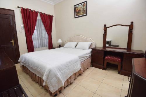 a bedroom with a bed and a dresser and a mirror at Ndalem Maharani Guest House in Yogyakarta