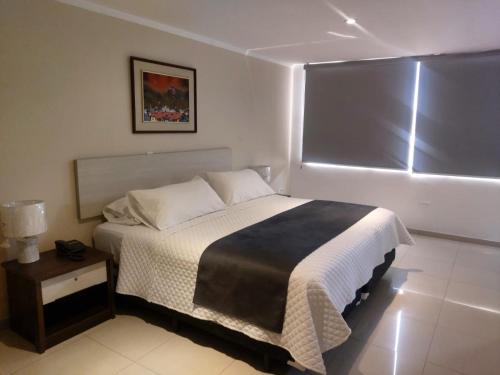 1 dormitorio con 1 cama grande y 1 mesa en Hotel Ejecutivo Portoviejo, en Portoviejo