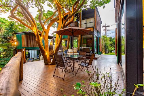 a patio with a table and chairs and a tree at Casa Natu Ilhabela Portinho in Ilhabela