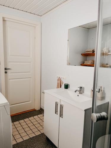 a white bathroom with a sink and a door at Charming house with wood stove near lake in Virserum