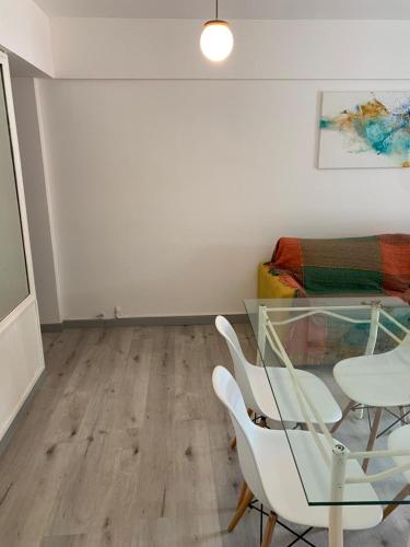 Excelente departamento de dos ambientes en Playa Grande Mar del Plata في مار ديل بلاتا: غرفة طعام مع طاولة زجاجية وكراسي بيضاء