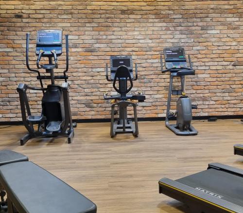 a gym with three exercise equipment in front of a brick wall at RentPlanet - Apartamenty Chlebova II in Gdańsk