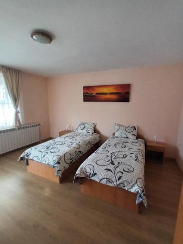 a bedroom with two beds and a painting on the wall at Guest rooms Bansko in Bansko
