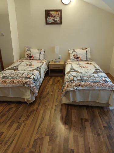 two beds in a room with wooden floors at Guest rooms Bansko in Bansko