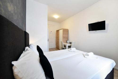 a bedroom with a white bed with a tv on the wall at Virtus Apartments and Rooms with Free Private Parking in Zagreb