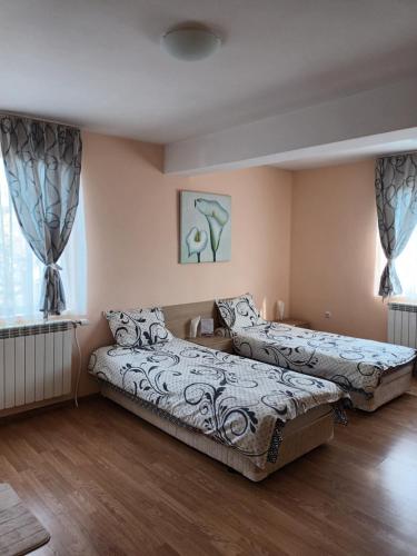 two beds in a room with wooden floors and windows at Guest rooms Bansko in Bansko