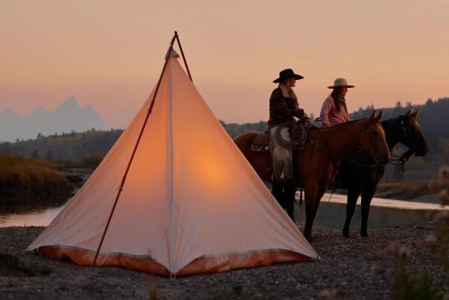 two people riding horses next to a tent at Heart Six Ranch in Moran