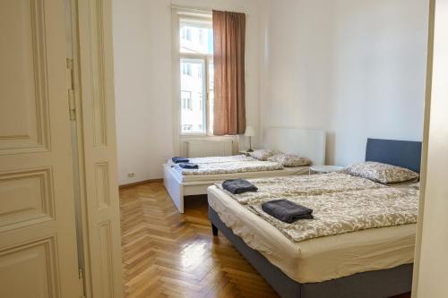 Cette chambre comprend 3 lits et une fenêtre. dans l'établissement Vienna Living Apartments - Gumpendorfer Straße, à Vienne