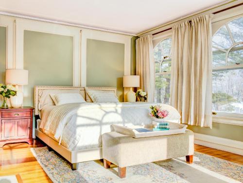 a bedroom with a bed and a table and windows at Gateways Inn in Lenox