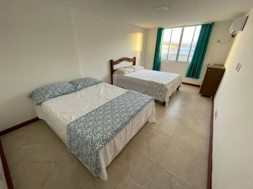 a bedroom with two beds and a window at Apartamento Lagoa de Saquarema in Saquarema