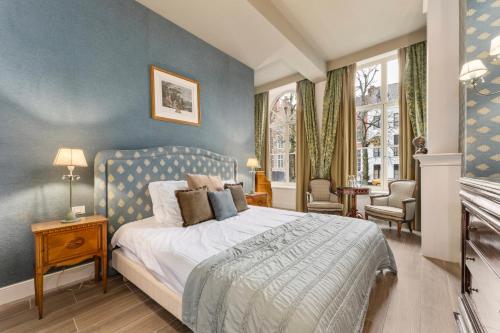 a bedroom with a bed with a blue wall at Canal Suites in Bruges