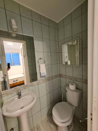a bathroom with a sink and a toilet and a mirror at Espectacular Casa Tres Pisos, cap. 21 Personas. in Algarrobo