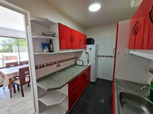 a kitchen with red cabinets and a sink and a table at Espectacular Casa Tres Pisos, cap. 21 Personas. in Algarrobo