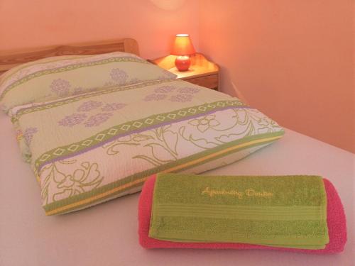 a bed with a green and white comforter and a towel at Apartmany Danka in Pavčina Lehota