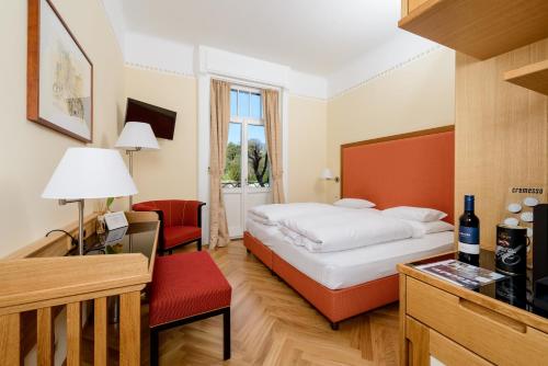 Habitación de hotel con cama y silla roja en Hotel Herzoghof en Baden