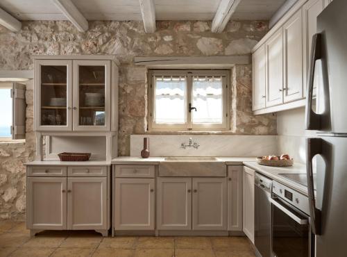 a kitchen with white cabinets and a sink at Orfos Villas in Agios Nikolaos