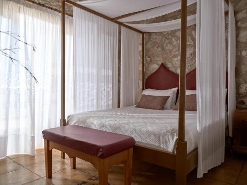 a bedroom with a four poster canopy bed with a bench at Orfos Villas in Agios Nikolaos