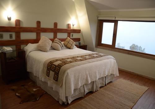 a bedroom with a bed and a large window at Hotel CasaEstablo by DOT Boutique in Pucón