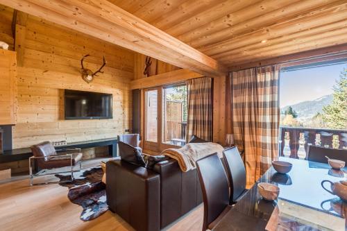 a living room with a table and chairs and a television at Wonderful appartement in a chalet with balcony - Megève - Welkeys in Megève