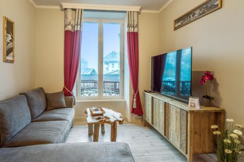 ein Wohnzimmer mit einem Sofa und einem Flachbild-TV in der Unterkunft Cosy apartment in the center of Chamonix - Welkeys in Chamonix-Mont-Blanc