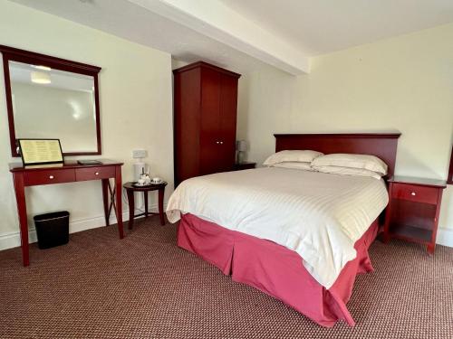 a bedroom with a large bed and a mirror at Calverts Hotel - Newport, Isle of Wight - RETURN CAR FERRY FROM 89 POUNDS in Newport