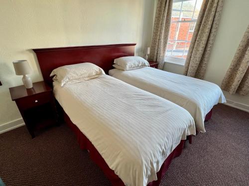 a hotel room with two beds and a window at Calverts Hotel - Newport, Isle of Wight - RETURN CAR FERRY FROM 89 POUNDS in Newport
