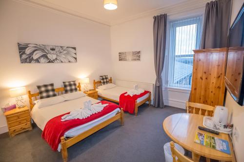 a room with two beds and a table and a desk at Granite City Guest House in Aberdeen