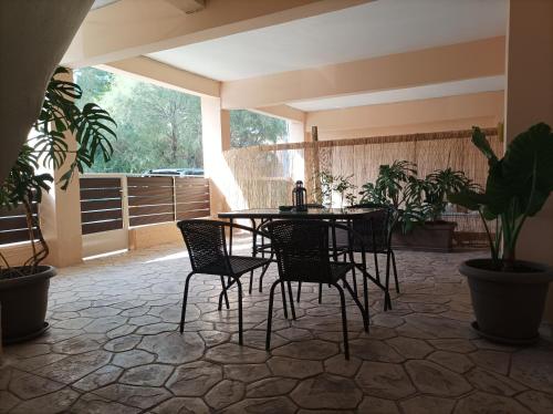 een patio met een tafel, stoelen en planten bij Happy holiday apartment in Artemida