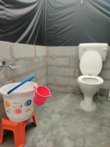 a bathroom with a toilet and a bucket with a toothbrush in it at My Manali Adventure in Jibhi