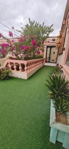 a balcony with a green yard with a bench and flowers at Al Moltaqua Chalet in Taif