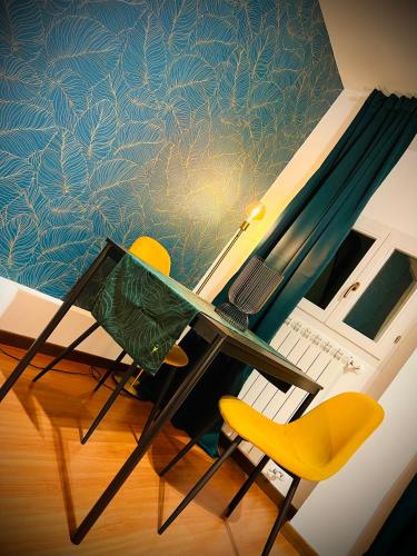 a dining table and a yellow chair in front of a wall at Crops City Stay Apartment 14 in Trieste
