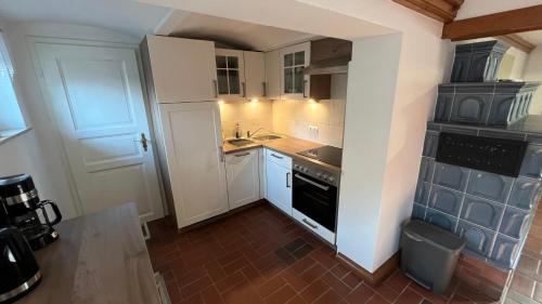 uma pequena cozinha com armários brancos e um fogão em Zur alten Eiche em Guhrow