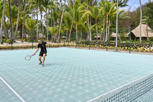 a man playing tennis on a tennis court at Le Bora Bora by Pearl Resorts in Bora Bora
