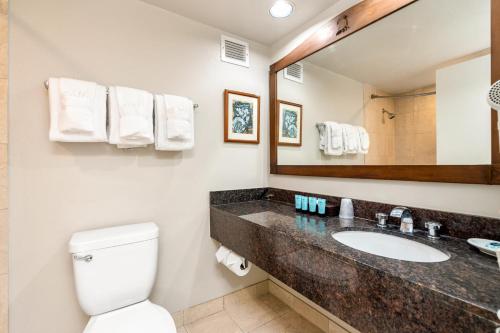 a bathroom with a sink and a toilet and a mirror at Luana Waikiki Resort #204 in Honolulu