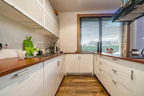 a kitchen with white cabinets and a large window at Amber Villa in Rīga