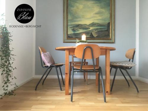 a dining room table with chairs and a painting at Design+Bodenseesicht=zuHause BLAU in Markdorf