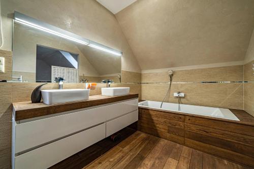 a bathroom with two sinks and a tub and a mirror at Amber Villa in Rīga