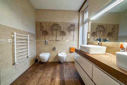uma casa de banho com 2 lavatórios, um WC e um espelho. em Amber Villa em Riga