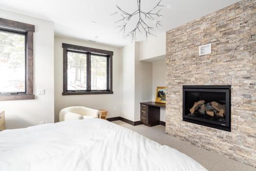 a bedroom with a fireplace and a white bed at Spanish Peaks Highlands Cabin 18 in Big Sky