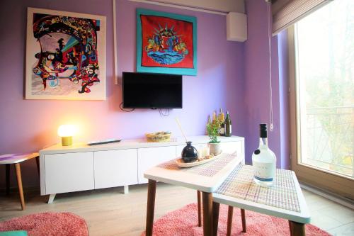 sala de estar con paredes de color púrpura, mesa y TV en Apartment Lothlórien Jahorina, en Jahorina