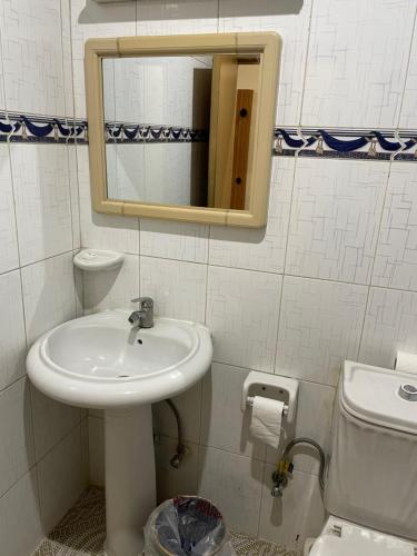 La salle de bains est pourvue d'un lavabo, de toilettes et d'un miroir. dans l'établissement Hotel Zaitona, à Erbil