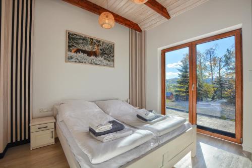 a bedroom with a bed and a large window at Domki Na Wzgórzu Woda JACUZZI SAUNA ROWERY in Zawóz