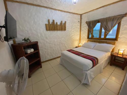 a bedroom with a bed and a fan and a television at Mamma Mía in Máncora