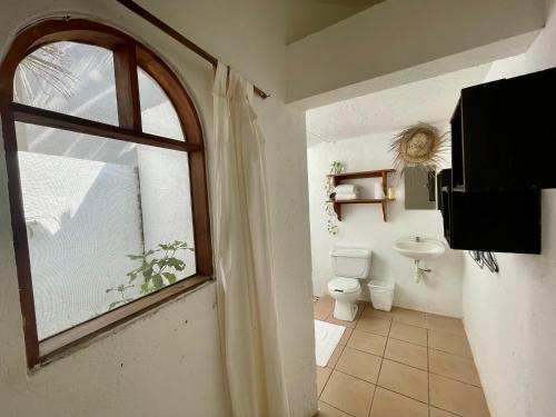 a bathroom with a window and a toilet and a sink at Quinta Feliz Troncones in Troncones